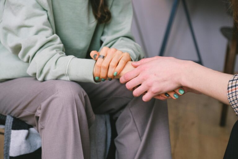 Two people holding hands in sympathy.