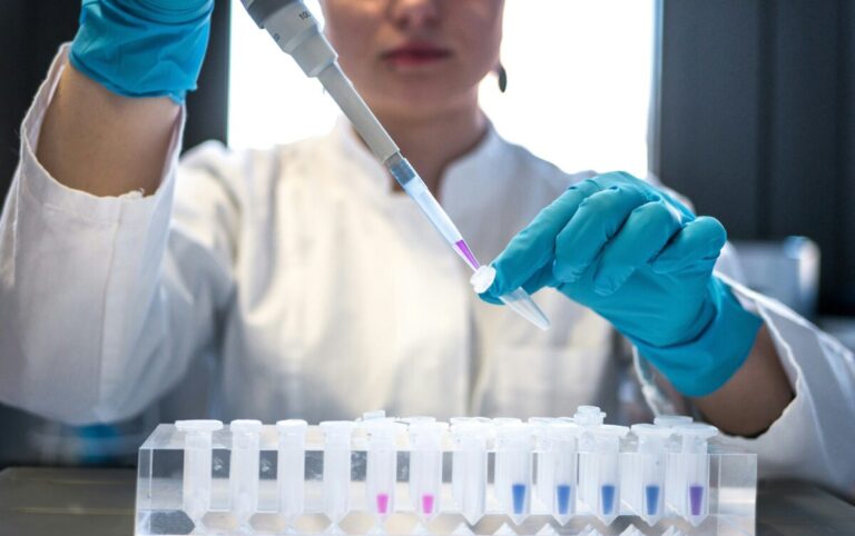 A female scientist working in a lab, putting small quantities of liquid into vials. By Julia Koblitz on Unsplash