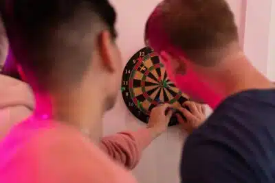 The backs of two young men at a dart board. By Kevin Malik on Pexels