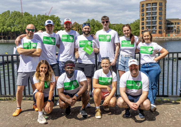 A group of employees from Clarion Housing Group pose in front of a river in NSPCC branded t-shirts nd shorts