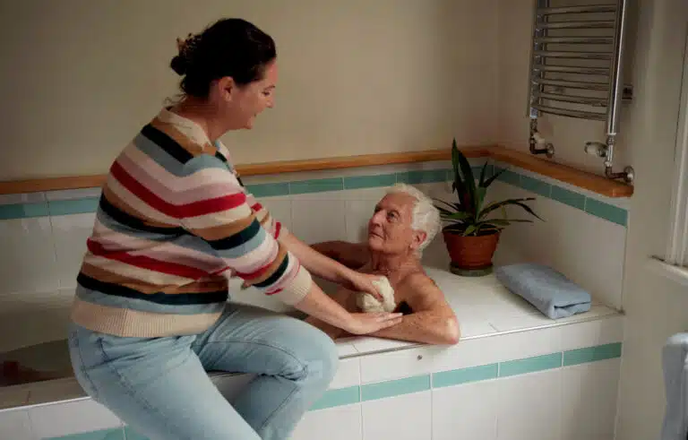 A woman helps her father bathe in an image from a Carers UK campaign