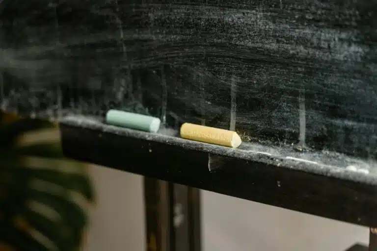 Close of chalk sitting on a blackboard. By Mart Production on Pexles