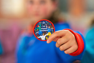 A Girl Guide holds out a new money skills badge