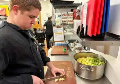 A young man who is supported by The Usual Place in Dumfries, Scotland, chops vegetables