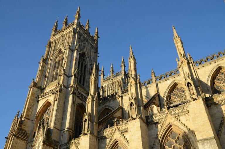 A shot looking up at York Minster, against a blue sky. By Robfoto on Pixabay