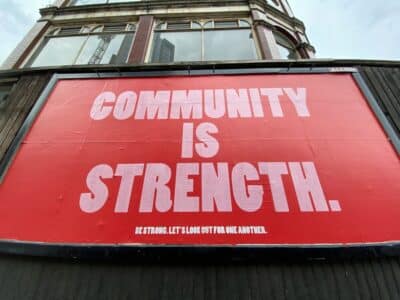 Community is strength. Large red poster on the side of a building.