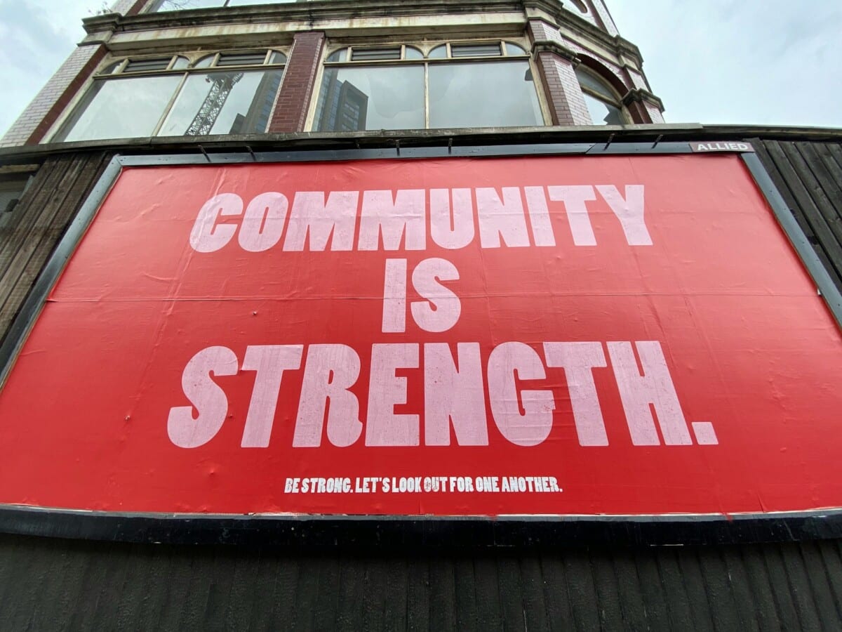 Community is strength. Large red poster on the side of a building.